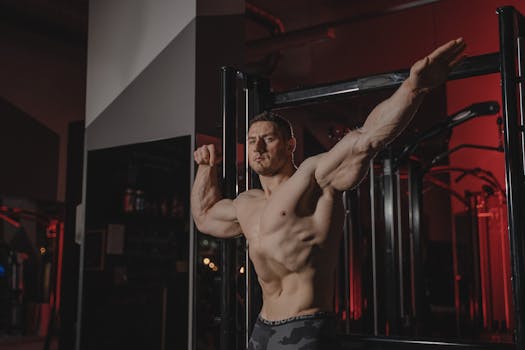 Strong and muscular man posing topless in a gym, showcasing fitness and strength.
