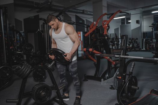 Muscular man lifting weights in a well-equipped gym for strength training.