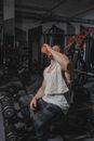 一名肌肉发达的男子在现代健身房激烈运动后，拿着毛巾休息喝水