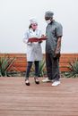 Man in Gray Button Up Shirt and Blue Denim Jeans Standing Beside Woman in White Long