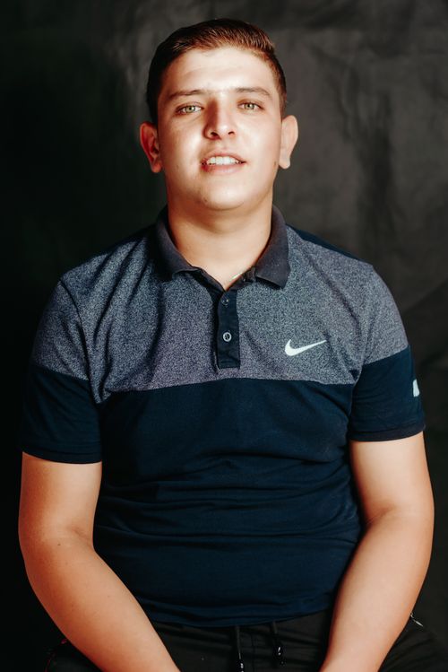 Free A young man wearing a blue polo shirt smiles against a dark background. Stock Photo