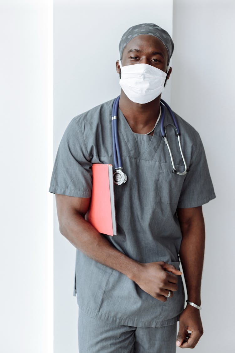 Man In Gray Scrubs Wearing Face Mask While Looking At The Camera