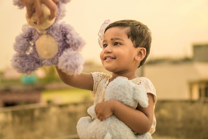 A toddler reaching for a stuffed toy