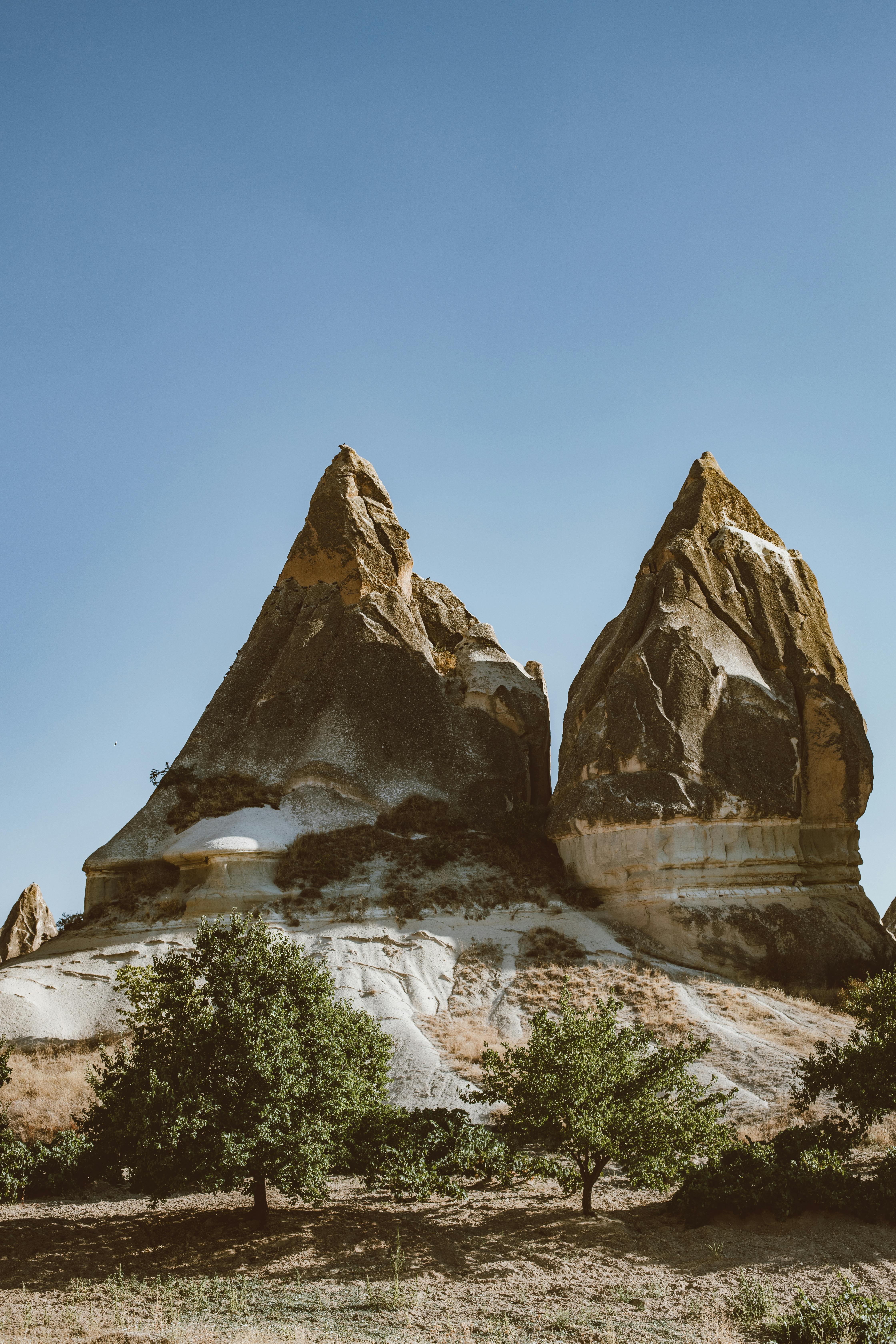 Dramatic sandstone peaks under a clear blue sky in Cappadocia, Turkey.