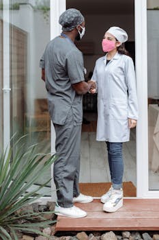 两名医疗保健专业人员在诊所外握手致意