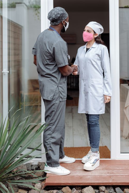 Free Two healthcare professionals greeting each other with a handshake outside a clinic. Stock Photo