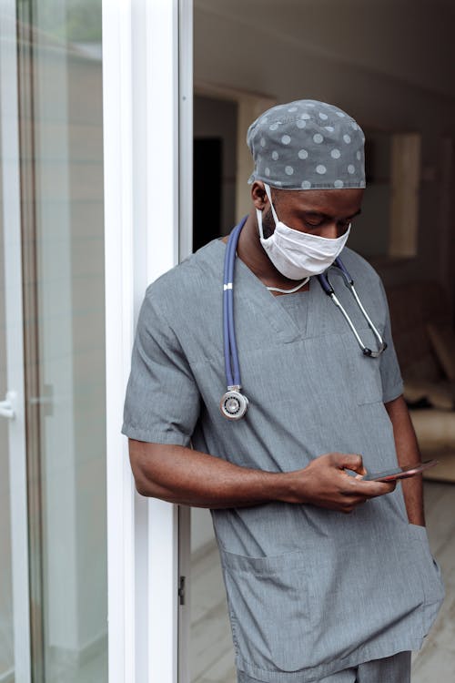 Free A Man in Scrub Suit Using His Cellphone  Stock Photo