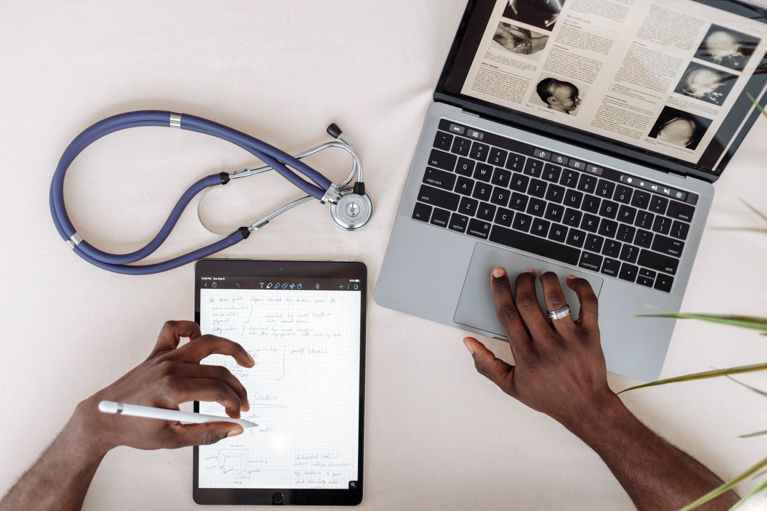 Medical professional using a laptop and tablet with a stethoscope