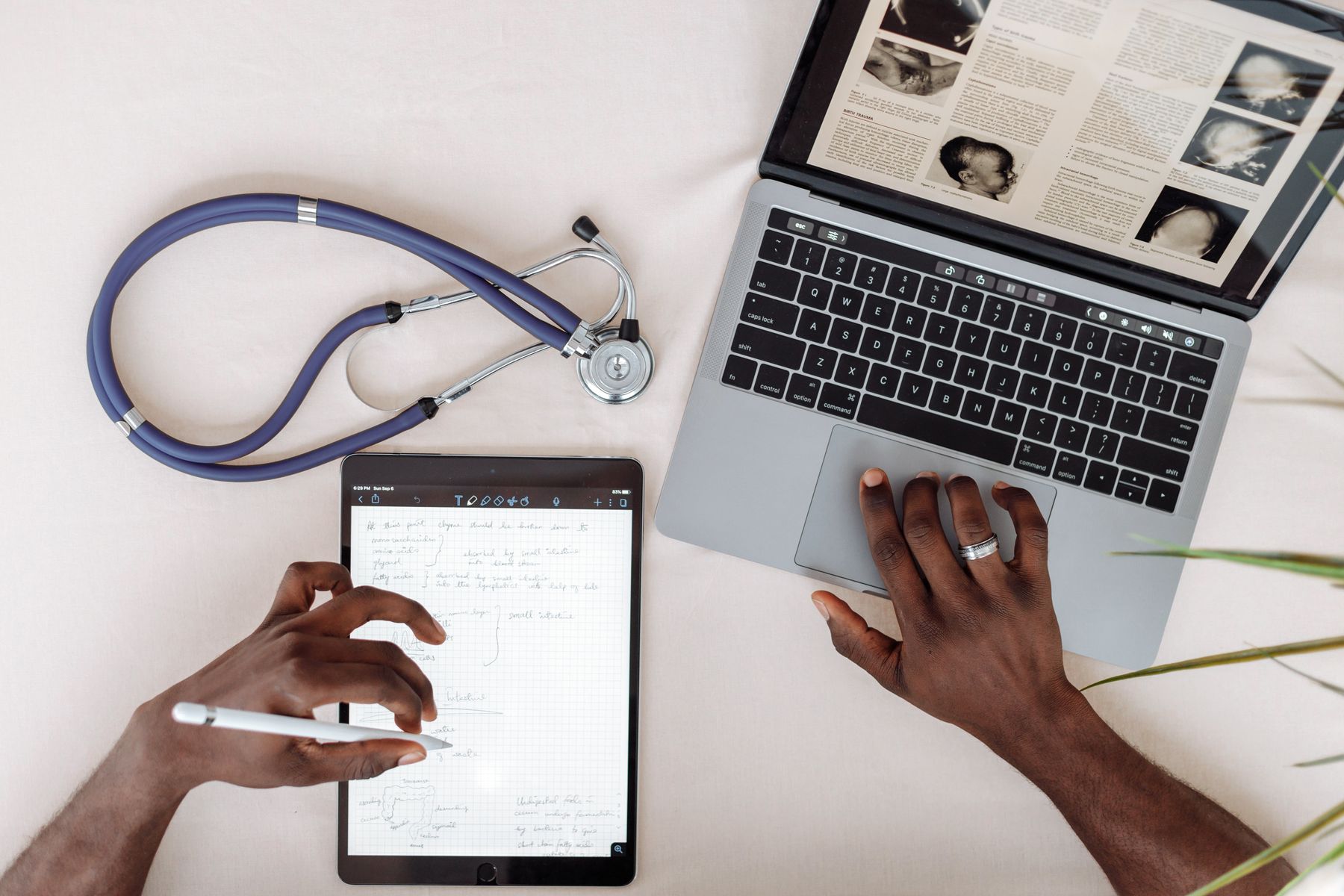 Healthcare professional using a tablet and laptop to review medical research