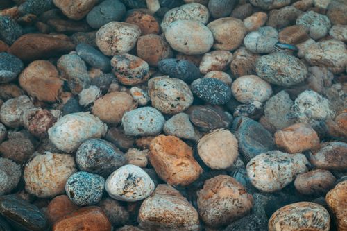 Free A close-up of smooth, multicolored river stones under clear water, capturing natural textures. Stock Photo