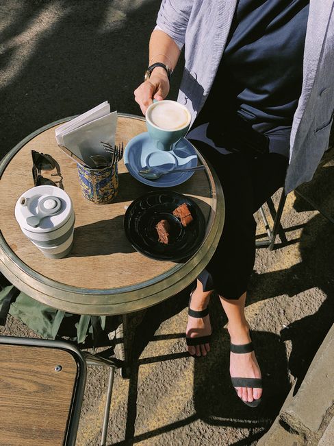 Person enjoying coffee and dessert at an outdoor cafe in Oxfordshire, England.