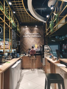 A cozy coffee shop interior with a barista preparing orders behind the counter.