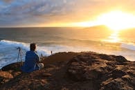 Person Sitting on Cliff Watching Sunset