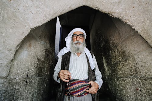 Бородатый мусульманин в традиционной одежде возле старого храма