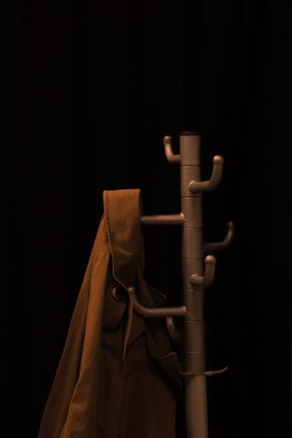 Veste de travail tabac suspendue sur un portant, studio sombre — photo Yahya Ozcan on Pexels
