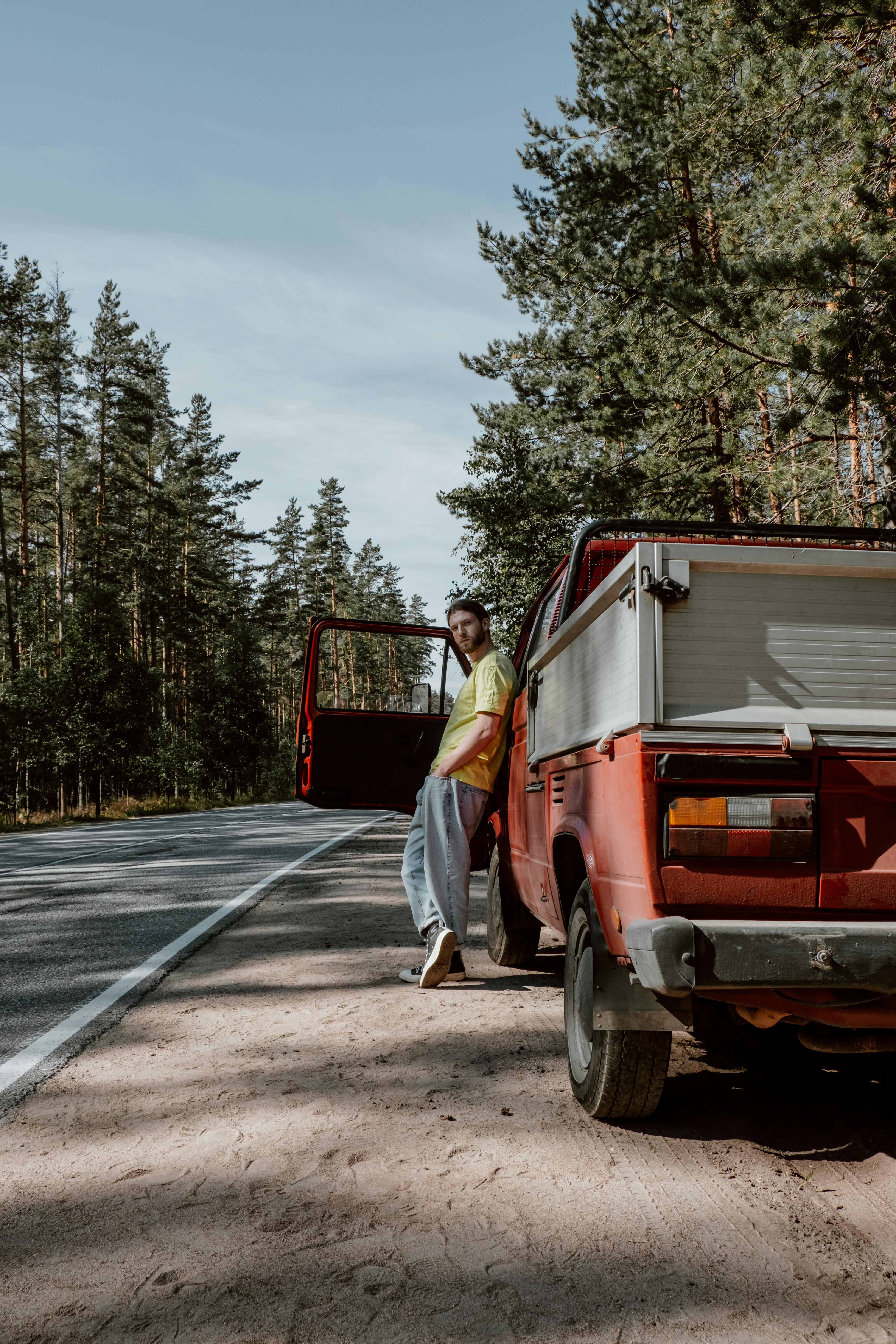 a man leaning on red pick up while looking at the camera