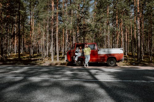 Red and White Pick Up Truck Parked on Road Surrounded by Trees
