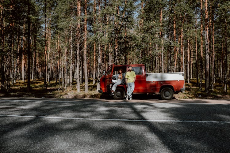 Red And White Pick Up Truck Parked On Road Surrounded By Trees