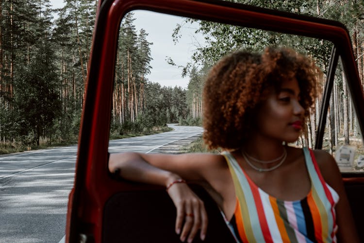 A Woman In Colorful Top Leaning By The Car Door