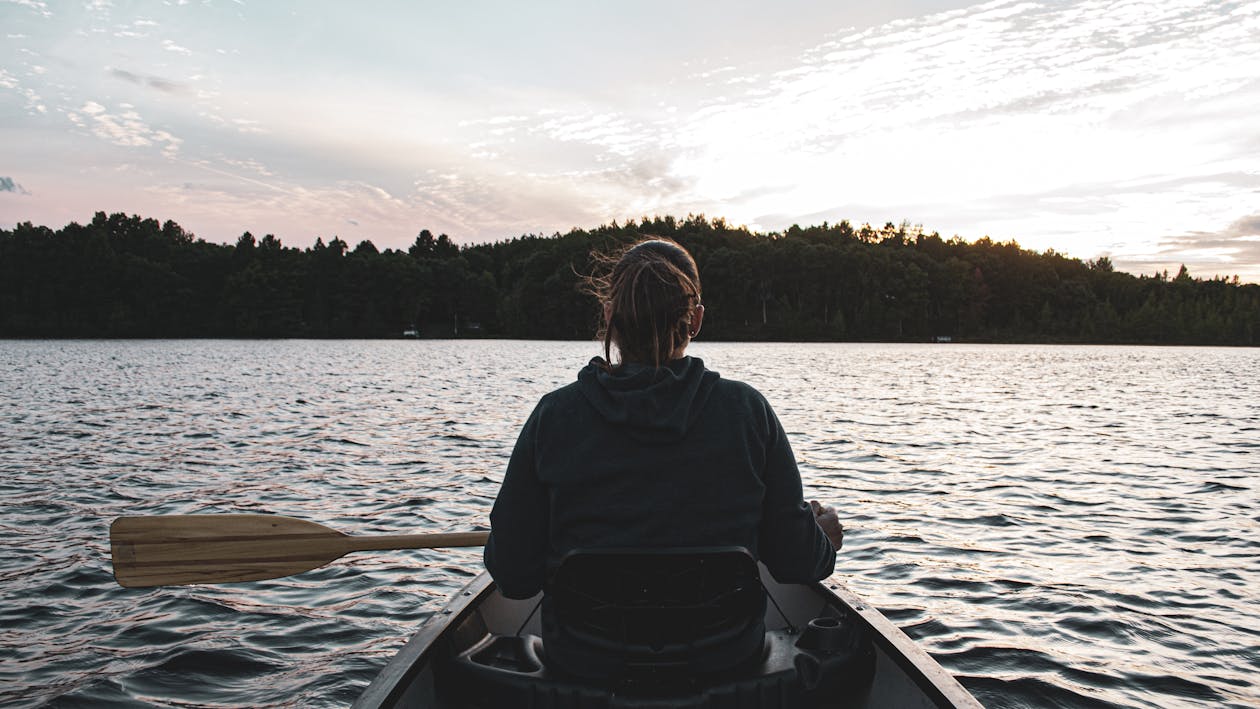 Back View of a Woman Sitting on the Boat holding Paddle · Free Stock Photo