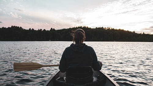 Free Back View of a Woman Sitting on the Boat holding Paddle Stock Photo