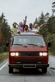 A group of friends enjoying a scenic road trip in a vintage red van, surrounded by lush forest.