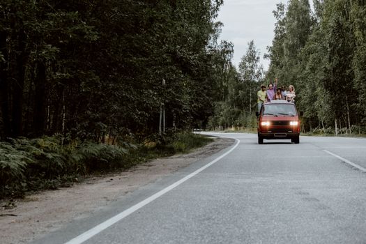 一群朋友在风景优美的森林道路上，享受着阳光明媚的公路旅行