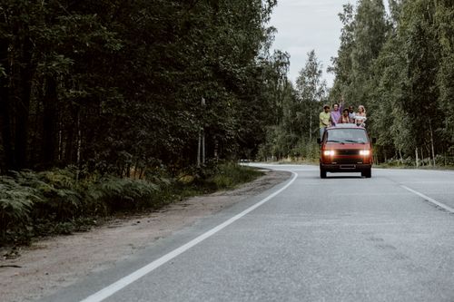 Free A group of friends enjoying a sunny road trip on a scenic forest road. Stock Photo