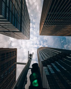 Low angle view of towering skyscrapers in Minneapolis, featuring a green stoplight and a dramatic sky.