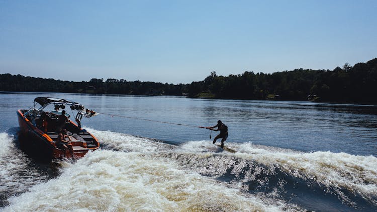 Unrecognizable Tourist Practicing Water Skiing On Lake With Motor Boat