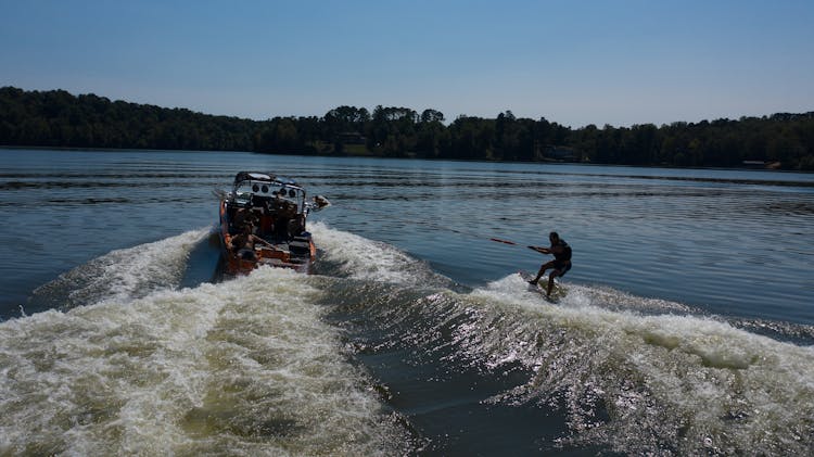 Silhouette Of Anonymous Traveler Practicing Water Skiing On River