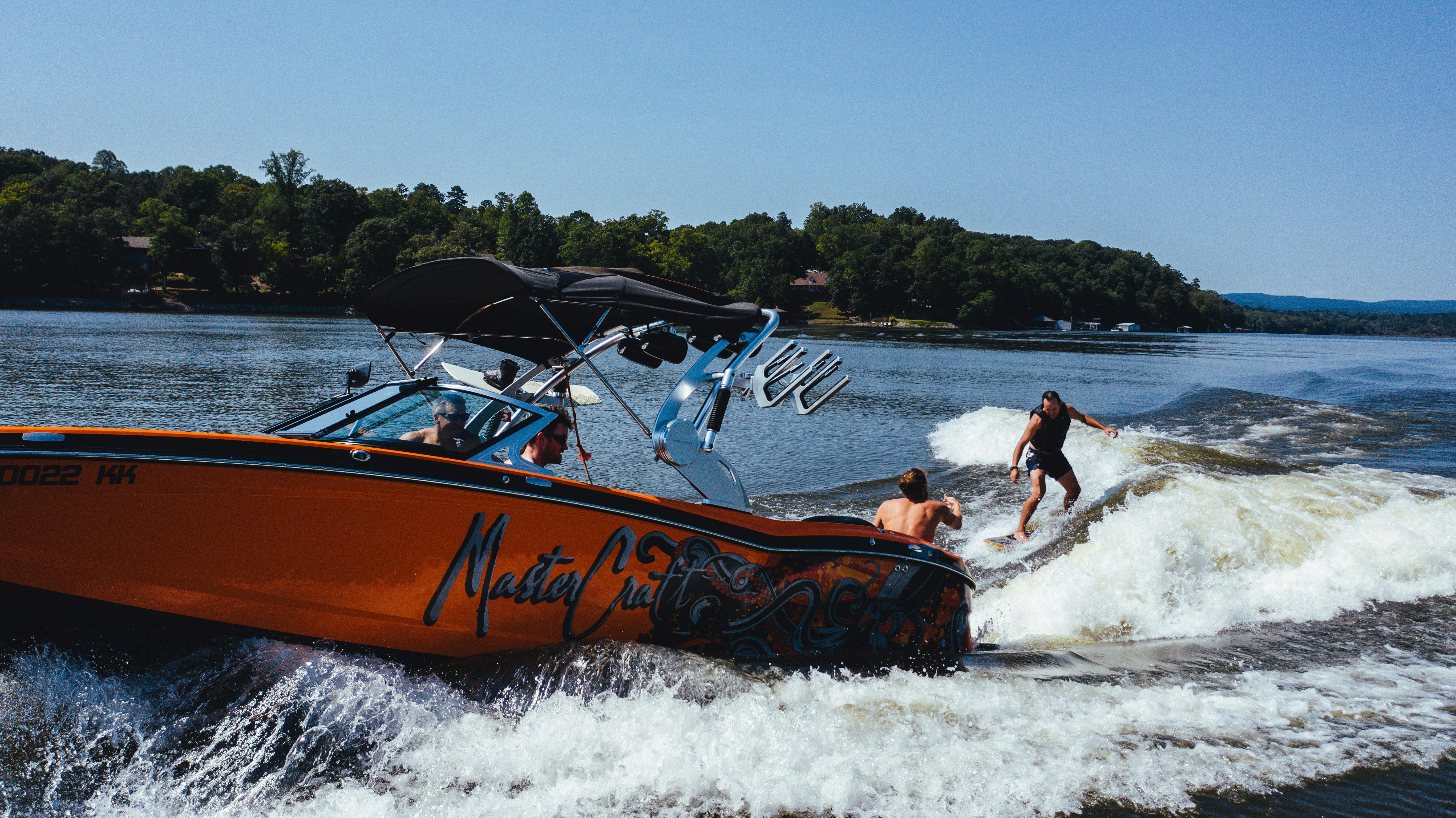 Anonymous athlete on wake board near motor boat on lake · Free Stock Photo