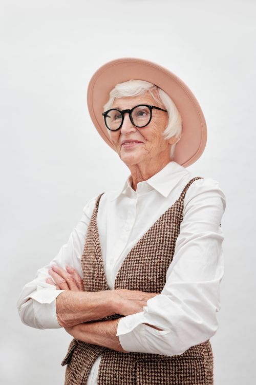 Free Fashionable senior woman with white hair and glasses, wearing a hat and stylish outfit. Stock Photo