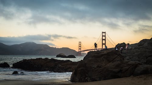 Free People on the Rocks with a Scenic View of the Golden Gate Bridge During Sunset Stock Photo