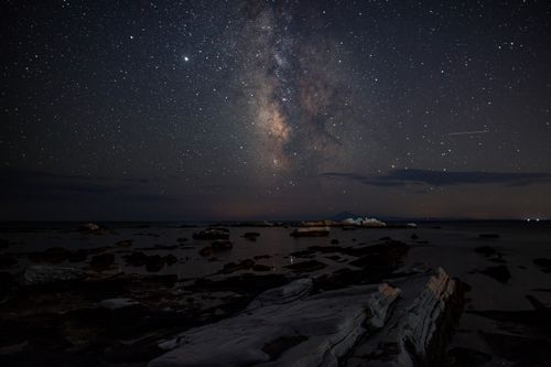 Free Stunning view of the Milky Way galaxy over a rugged shoreline with rock formations at night. Stock Photo