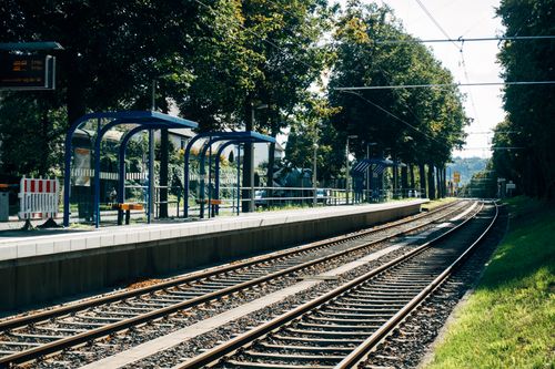 Free Scenic view of a train station platform and tracks in Stuttgart surrounded by greenery. Stock Photo