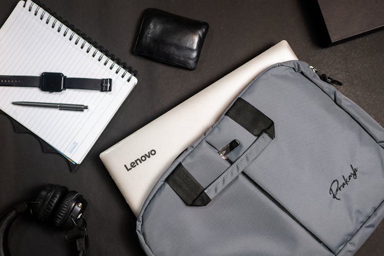 Laptop With A Bag Near A Notebook With Pen And Watch