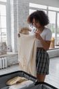 Black woman packing suitcase in room