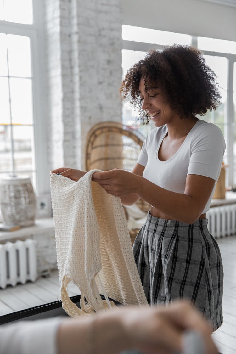 Cheerful Black Woman Packing Clothes