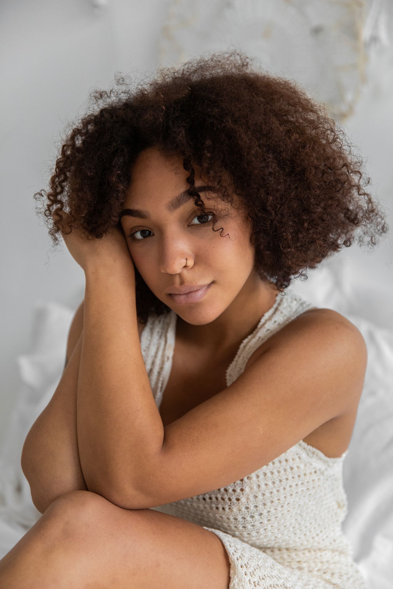 Young woman with natural curly hair resting in a bright bedroom