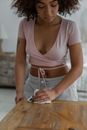 Crop African American female wiping wooden table while doing housework routine  in apartment