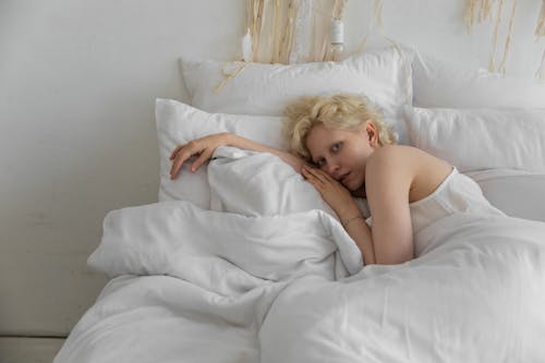 Free Calm woman lying on comfortable pillows in bedroom Stock Photo
