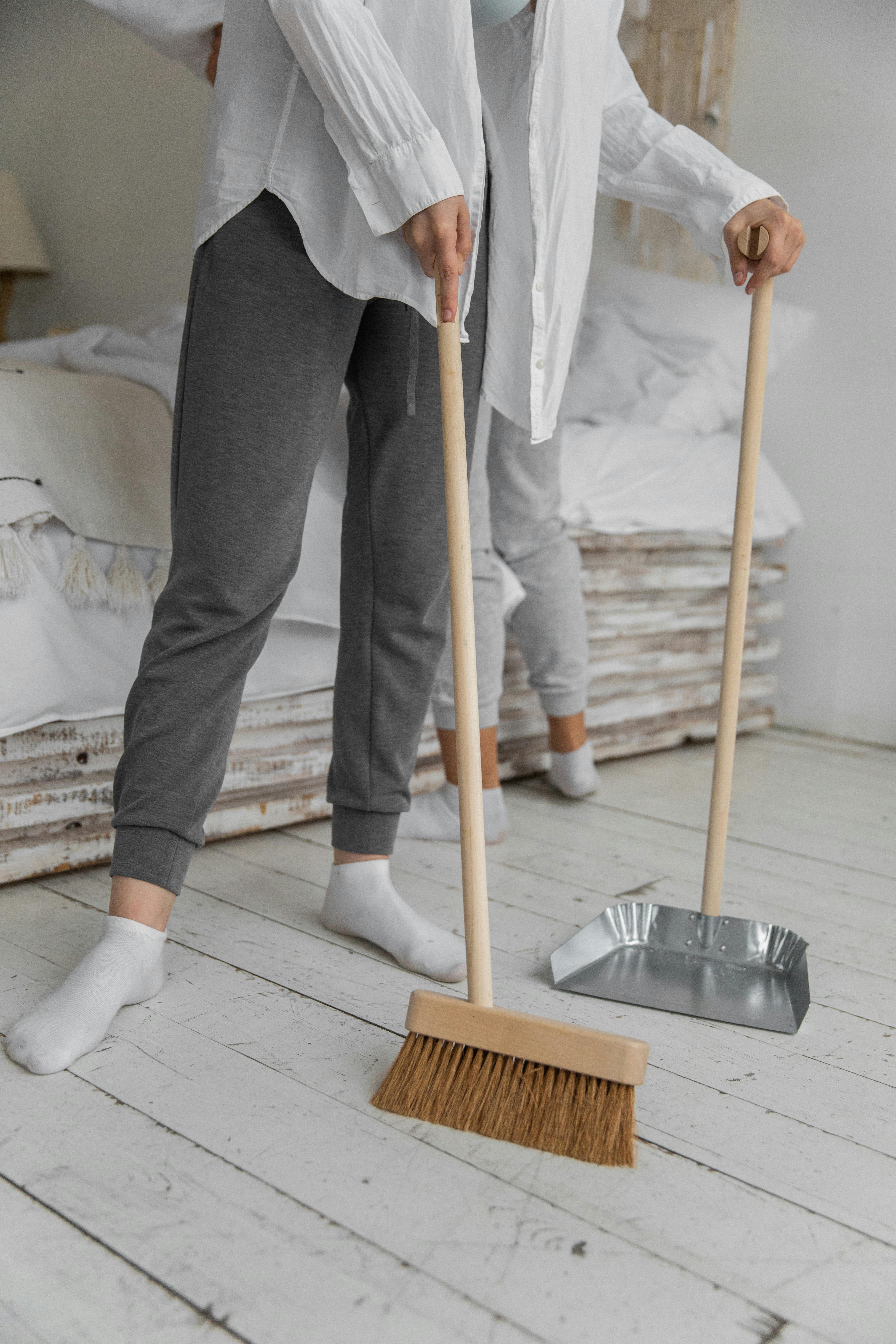 anonymous women sweeping floor during housework at home