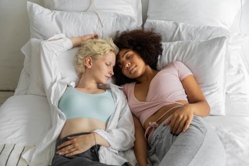 From above of peaceful multiracial homosexual couple lying close during sleep at weekend in cozy room