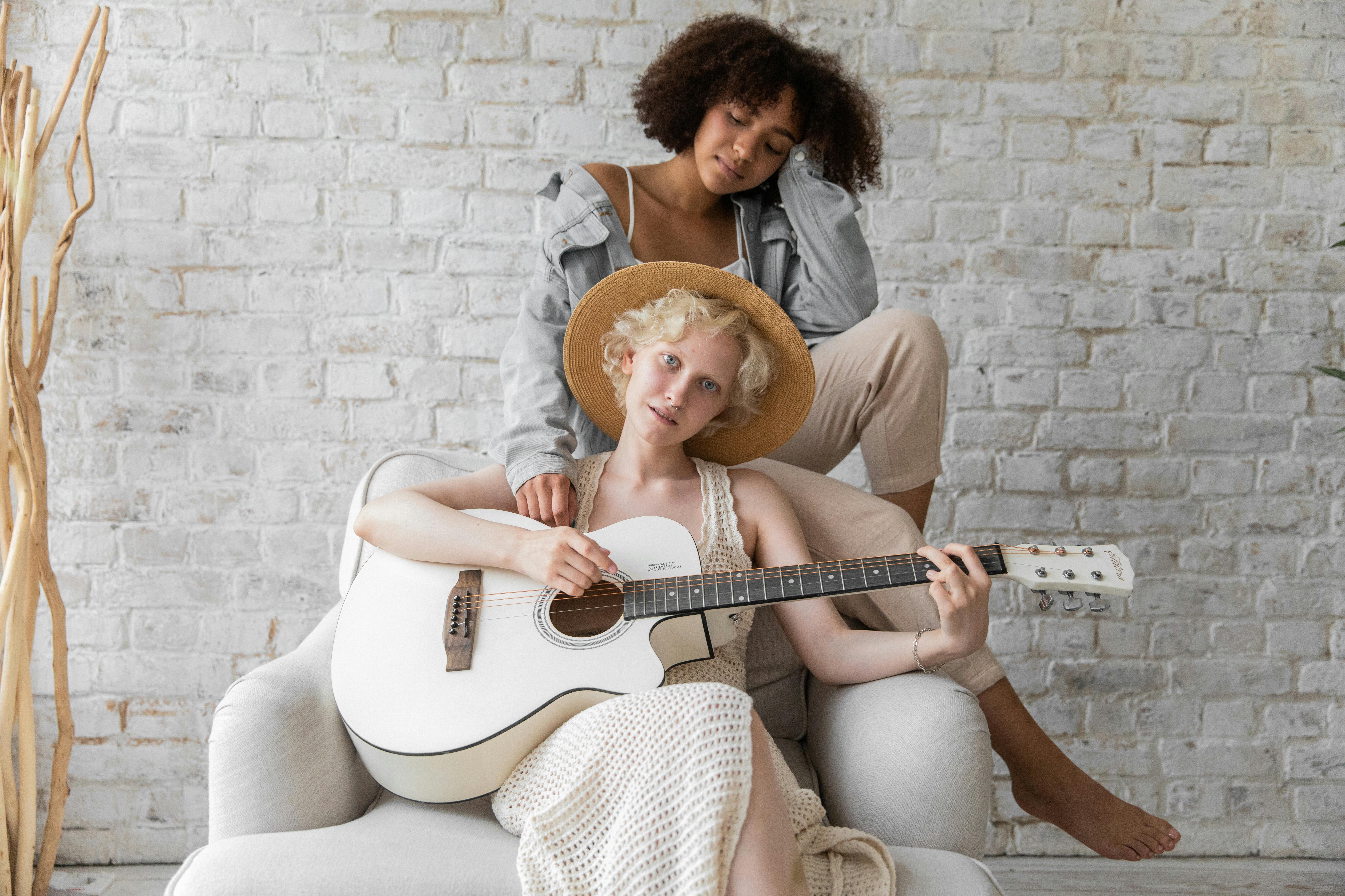 calm woman playing guitar with black lesbian female