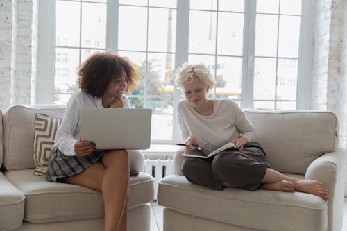 Free Cheerful young multiethnic girlfriends discussing project while working on netbook at home Stock Photo