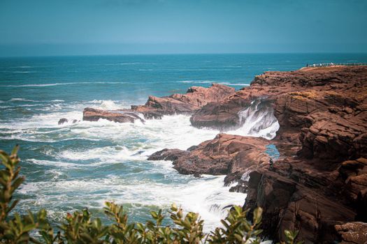 在明亮的天空下，海浪拍打着俄勒冈州岩石海岸线的悬崖，景色迷人