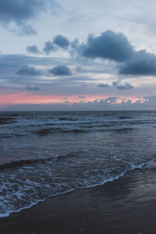 Free Astonishing view of blue ocean with waves and sandy beach with colorful cloudy sky on horizon Stock Photo
