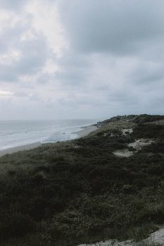 Majestic view of grassy long coastline washed by calm blue ocean in cloudy weather during daytime