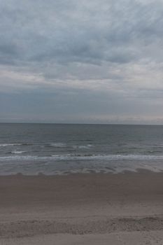 Picturesque view of beach with fine sand and boundless ocean with waves under cloudy blue sky